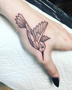 a small bird tattoo on the left hand is shown in black and grey ink with an arrow