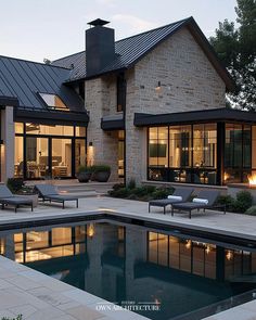 a house with a swimming pool in front of it and two lounge chairs next to the pool