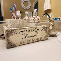 an old wooden sign sitting on top of a bathroom counter next to a sink and mirror