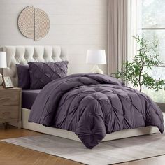 a bed with purple comforter and pillows in a room