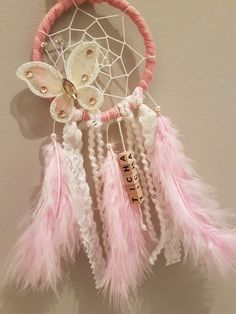 a pink and white dream catcher hanging on the wall