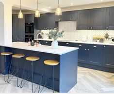 a kitchen with an island and bar stools in the center, surrounded by dark wood cabinets