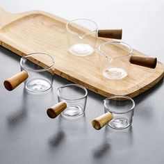 four shot glasses on a cutting board with wooden handles