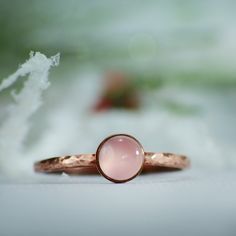 This Copper Rose Quartz Ring features a 6 mm cabochon that has been securely set in a highly polished fine copper bezel. The band is made of a sturdy round Copper wire that has been given a hammer texture, then carefully finished for comfortable wear. Our setting process involves carefully tightening the bezel around the stone, creating a water-tight seal with no stone movement. These beautiful rings make unique promise rings, lovely stacking rings, great birthstone rings, or just a wonderful lo Hand Forged Round Moonstone Ring, Stackable Rose Gold Moonstone Ring, Stackable Round Moonstone Ring In Rose Gold, Rose Gold Stackable Rings With Bezel Setting For Gift, Rose Gold Gemstone Stackable Rings, Rose Gold Ring With Round Stone For Gift, Rose Gold Ring Gift, Rose Gold Moonstone Ring With Birthstone, Rose Gold Moonstone Birthstone Ring