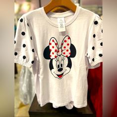 a minnie mouse t - shirt with polka dots on it is hanging in a store