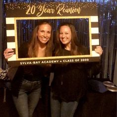 two women standing next to each other holding up a sign