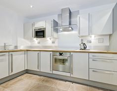 an empty kitchen with white cabinets and stainless steel appliance on the counter top