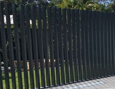 an image of a black fence in the middle of a yard with grass and trees behind it