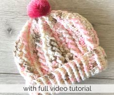 a crocheted hat with a pink and white pom - pom on top