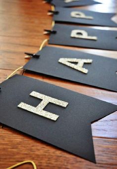 black and gold birthday banner with glitter letters on it, sitting on a wooden table