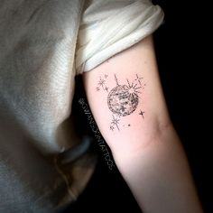 a woman's arm with a tattoo on it that has an image of the moon and stars