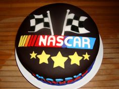 a birthday cake with the name nascar on it and stars in the middle, sitting on a wooden table