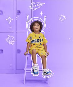 a little boy sitting on top of a chair in front of lockers with space drawings