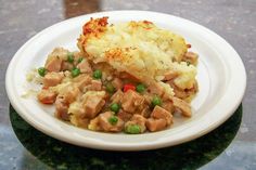 a white plate topped with mashed potatoes covered in meat and vegtables