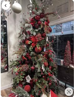 a christmas tree with red ornaments and greenery in the center, surrounded by other decorations