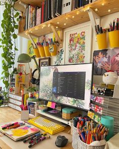 a desk with a computer monitor, keyboard and various office supplies on it in front of a bookshelf