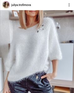 a woman is wearing a white sweater and jeans