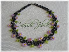 a necklace made with beads and flowers on a white lace tablecloth that says chick glacer