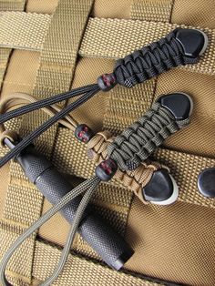 two black and brown knives are laying on some tan fabric with metal pins sticking out of them