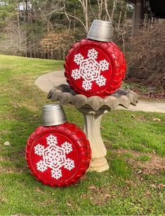 two red and silver tin canisters sitting on top of a birdbath