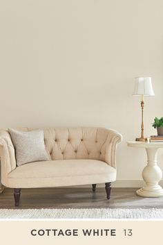 a living room with white walls and furniture in the corner, there is a lamp next to the couch