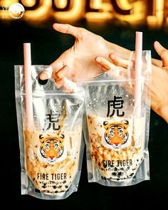 two people holding up cups with drinks in them and the words fire tiger written on it