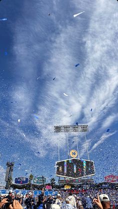 people are throwing confetti on the field at a football game with blue sky and white clouds