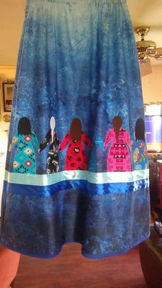 a blue curtain with three black women in colorful dresses hanging from it's side