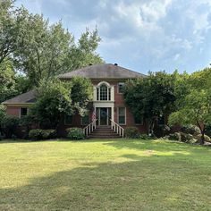 a brick house with green grass and trees