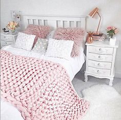 a white bed topped with pink pillows and blankets