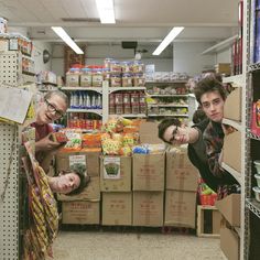 two men in a grocery store pointing at the camera with one man's head upside down