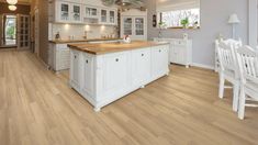 a large kitchen with wooden floors and white cabinets is pictured in this image from the inside