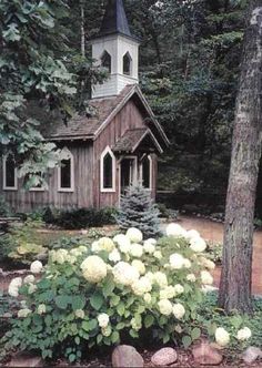 a small wooden church surrounded by trees and flowers