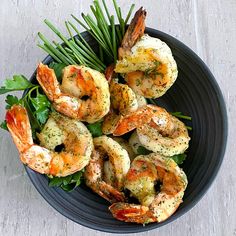 a black plate topped with shrimp and greens