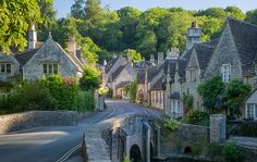 an old town with stone buildings and cobblestone roads in the foreground, surrounded by lush green trees