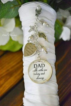 a white vase filled with flowers and a keychain that says dad on it