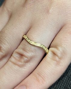 a close up of a person's hand with a gold ring on their finger