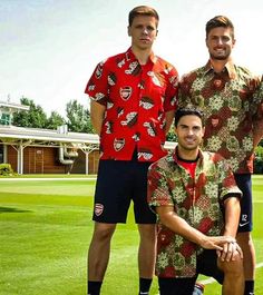 three men in matching shirts standing on a soccer field