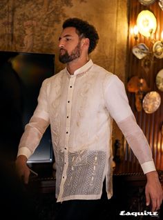 a man standing in front of a tv wearing a white shirt and black pants with buttons