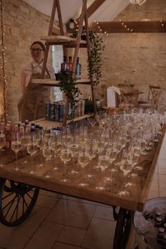 a man standing next to a table filled with wine glasses on top of a wooden cart