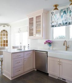 a kitchen with pink cabinets and white counter tops, an oven, dishwasher and sink