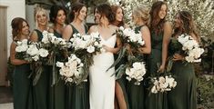 a group of women standing next to each other in green dresses holding bouquets with white flowers