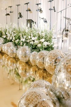 there are many shiny balls and flowers in the center of this table with gold sequins on it