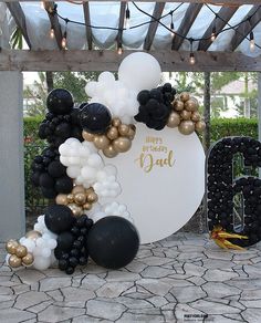 a balloon arch with black, white and gold balloons