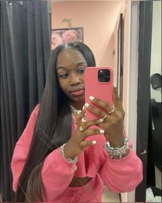 a woman taking a selfie in front of a mirror wearing a pink shirt and bracelets