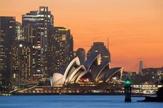 the sydney opera house is lit up at night in front of the cityscape