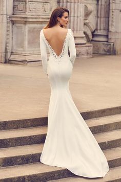 a woman in a white wedding dress standing on steps with her back to the camera