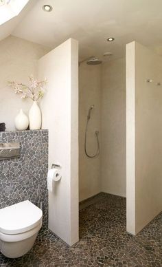 a white toilet sitting in a bathroom next to a walk in shower and tiled floor