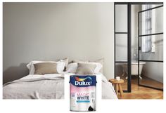 a can of dulux white paint sitting on top of a bed in a bedroom