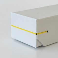 a white box with yellow string on the side sitting on top of a gray table